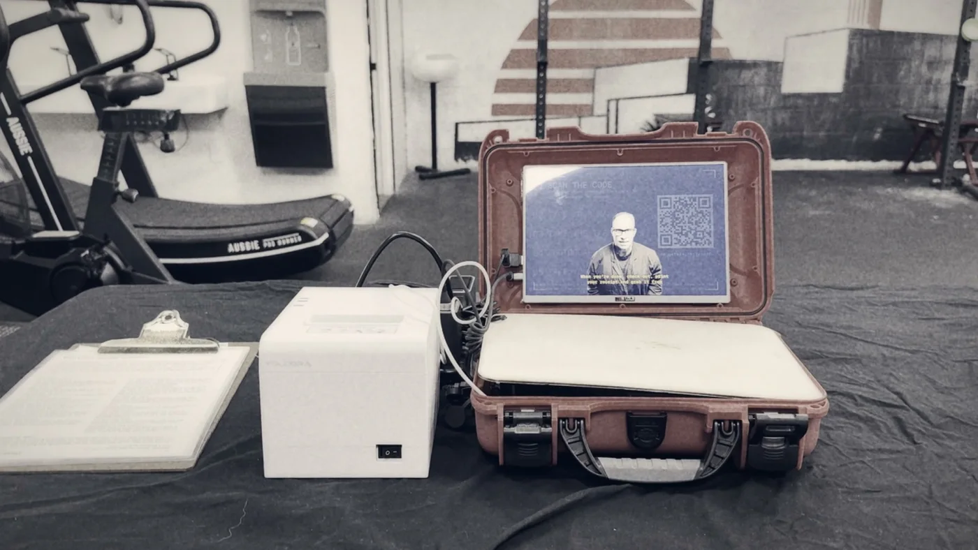 The rig — display, printer, and the phone endpoint, on a table in the middle of the gym